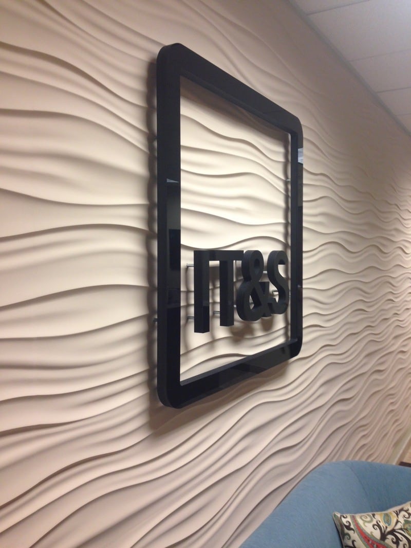 3d dimensional letter sign IT&S 3D logo sign: black dimensional letters and frame on a wave-textured wall