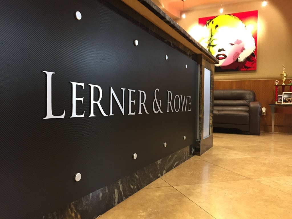 interior lobby sign Lerner & Rowe lobby sign: silver letters on a black wall panel beside the reception desk