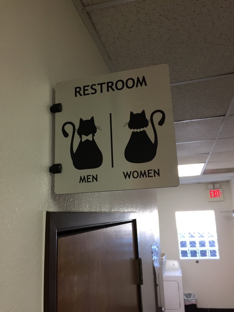 restroom sign Restroom sign with cat pictograms for men and women above a doorway