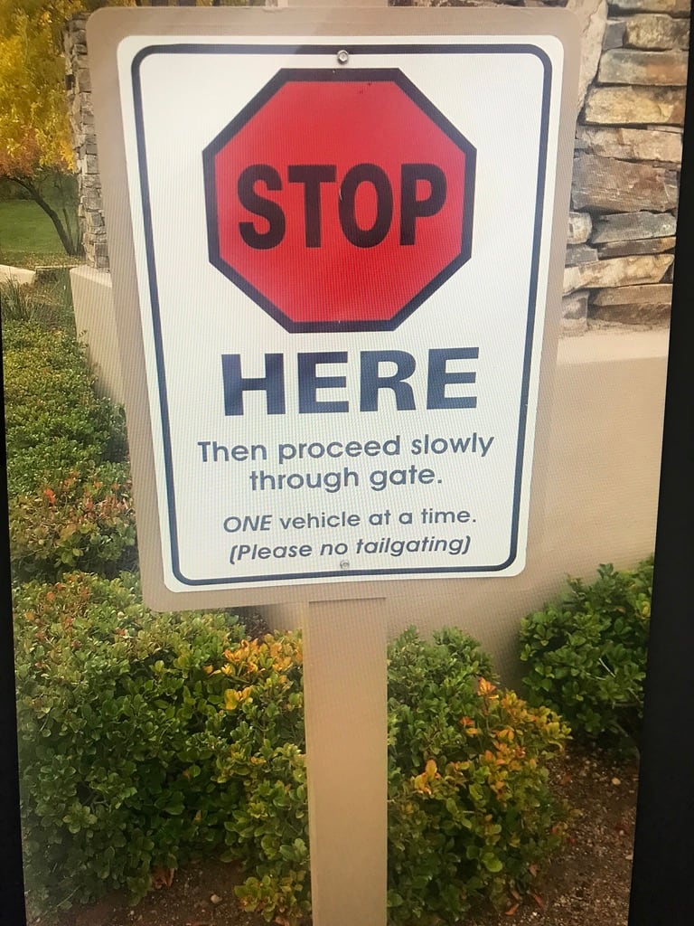 aluminum sign on post Aluminum sign on a post: Stop Here, then proceed slowly through gate