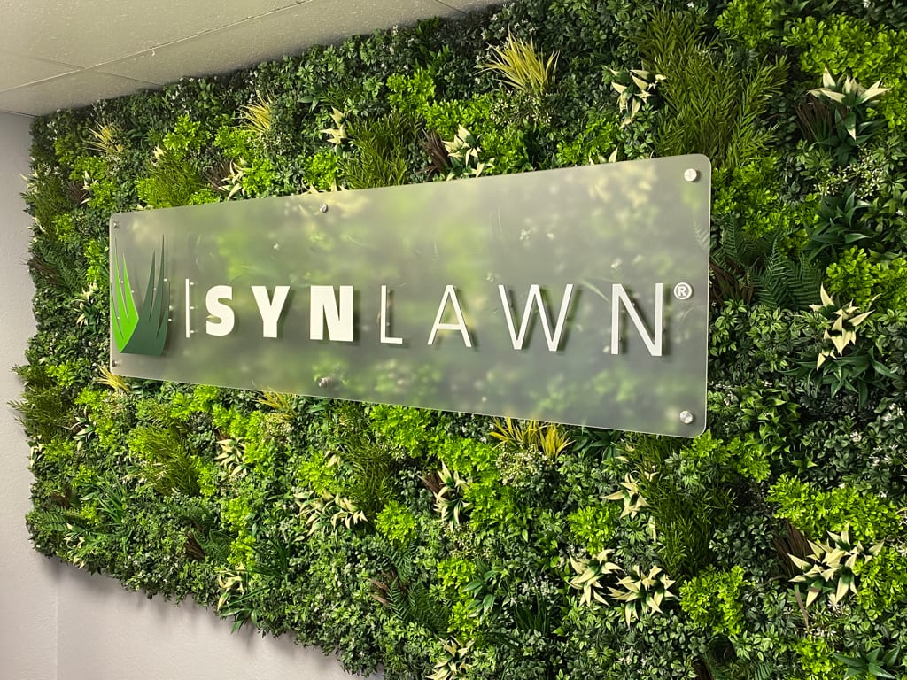 frosted acrylic lobby sign SynLawn frosted acrylic sign on a green plant wall