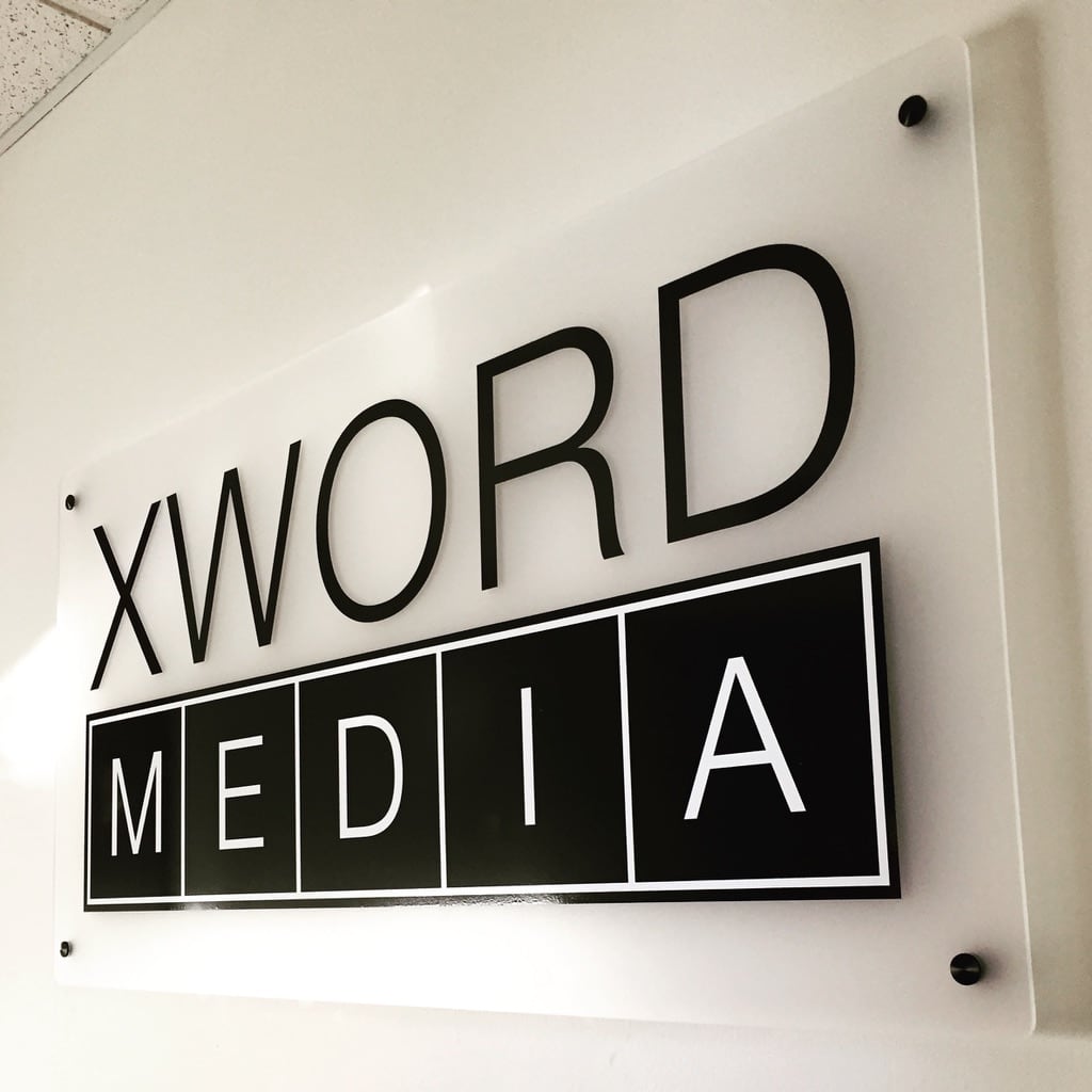 acrylic standoff sign XWord Media sign: black logo on a clear acrylic panel with standoffs
